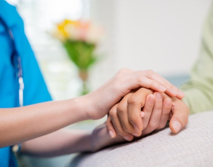 Clinician holding an older patient’s hands in reassurance Clinician holding an older patient’s hands in reassurance